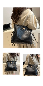 Close-up of quilted pattern and gold metal plaque on a black leather tote bag