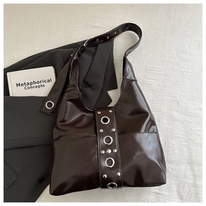 Detailed view of glossy dark brown rivet shoulder bag with silver metallic punk accents