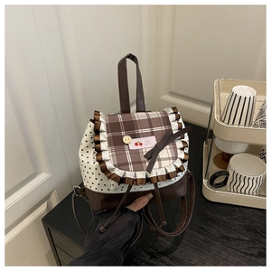 Detail of sweet plaid backpack featuring cherry label and decorative lace bow details