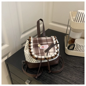Detail of checkered flap with white lace trim and cherry patch on a sweet school backpack