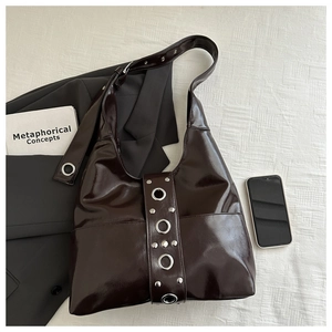 Macro detail of dark brown punk tote bag with large silver metal grommets and rivets