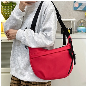 Macro detail of red dumpling crossbody bag showing woven zipper pull and nylon texture