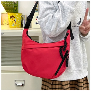Detail of red nylon tote bag with side zipper and woven strap pull shown on model