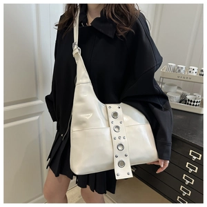 Close-up of beige punk style shoulder bag with silver eyelets on wide strap