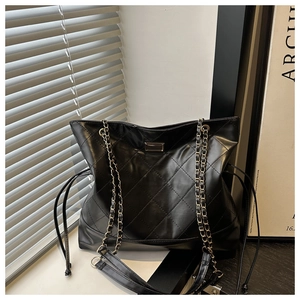 Close-up of quilted pattern and gold chain strap on the black faux leather tote bag