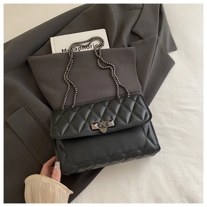 Close-up of black quilted leather texture with luxury heart metal lock and chain strap