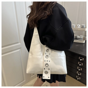 Detail of silver rivets and metal eyelets on the white punk-style shoulder bag strap