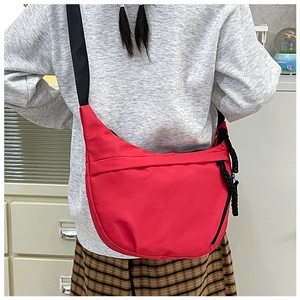 Detail of red crescent messenger bag with wide adjustable strap and woven zipper pullers