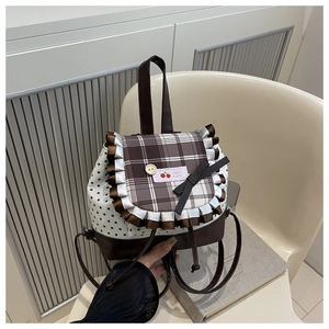 Detail of sweet bow backpack featuring star pattern, plaid flap, and Hello cherry tag