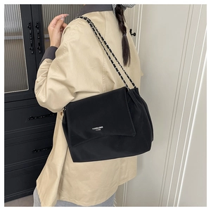 Detail of black matte leather shoulder bag with chain strap and printed brand logo