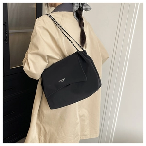Chic black leather tote bag with metal chain strap shown on model shoulder
