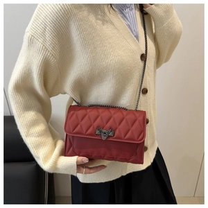 Detailed view of red quilted PU leather crossbody bag with metallic V-lock and chain strap
