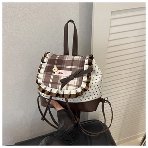 Detail of checkered backpack with lace trim, cherry label, and small star patterns