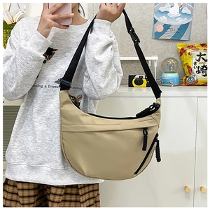 Close-up of beige half-moon crossbody bag featuring durable nylon and black strap