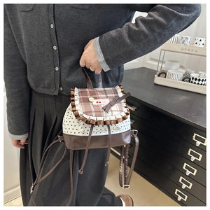 Detail of a plaid drawstring backpack with ruffles, star prints and cherry emblem decoration