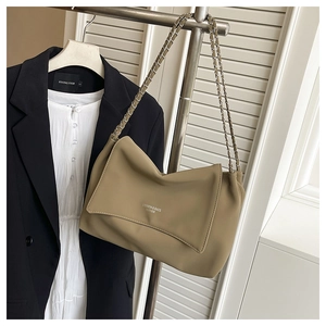 Detail of khaki leather shoulder bag with chain strap styled on a black blazer