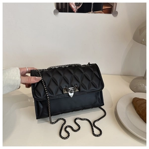 Detailed shot of a black quilted crossbody bag featuring a silver heart-shaped metal lock