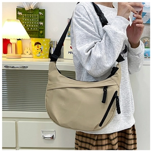Detail of adjustable black nylon shoulder strap on khaki crescent tote bag for women
