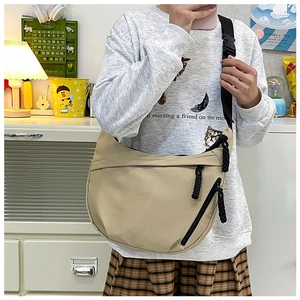 Close-up of beige nylon half-moon crossbody bag with black strap and braided zipper pull