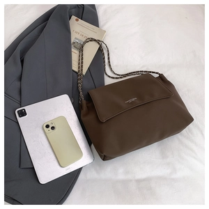 Detailed view of dark brown leather pillow bag featuring an elegant metal chain strap