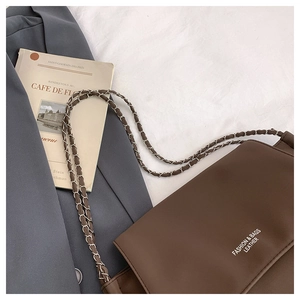 Detailed view of brown leather bag with chain strap and elegant brand logo