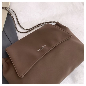Detail of vintage brown shoulder bag showing matte texture and woven chain strap