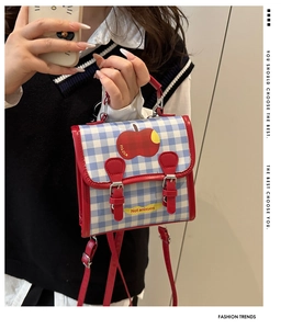Detail of red and blue checkered student backpack with apple print and buckle closure