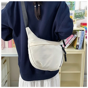 Detail of off-white crossbody bag featuring durable nylon fabric and woven rope zipper pull