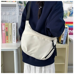 Detail of cream canvas dumpling bag with adjustable strap and dual zipper closure