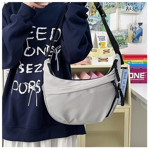 Close-up of a light grey nylon hobo bag featuring adjustable wide strap and side woven rope