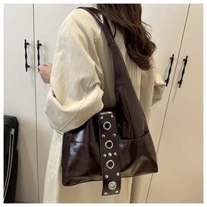 Detail of dark brown vintage rivet hobo bag with polished finish and silver grommets