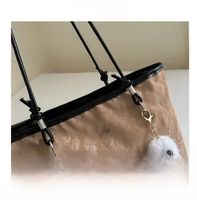 Macro detail of khaki textured tote bag with metal Balena logo and plush monster charm