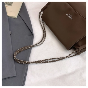 Detail of vintage brown leather pillow bag featuring chain strap and fashion text logo