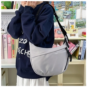 Detail of light gray crescent bag made of durable matte nylon with smooth black zipper