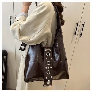 Detail of dark brown rivet shoulder bag with shiny oil wax finish and metallic studs
