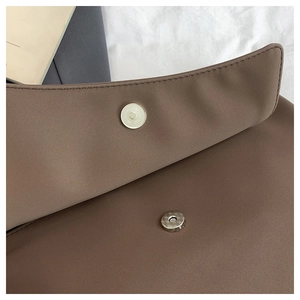 Detail of the magnetic closure on a brown vintage crossbody bag with smooth matte texture