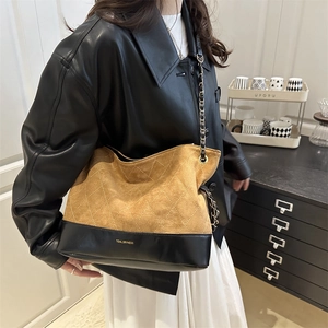 Close-up of quilted brown suede tote bag with golden brand logo and chain strap