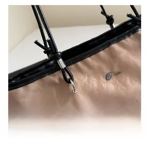 Detail of light khaki tote bag featuring pleated texture, black straps and metal logo