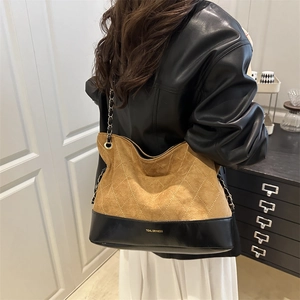 Detailed view of quilted suede tote bag with gold chain strap worn by a model
