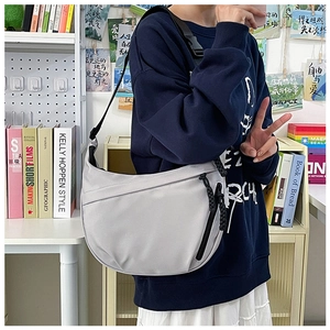 Detail of light grey nylon crescent bag with adjustable strap and front zipper pocket