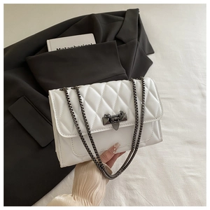 Detail of quilted leather crossbody bag with chain strap and metallic lock on a blazer