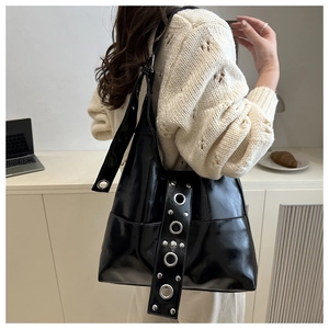 Close-up of a black glossy punk tote bag with silver rivets and studs for women