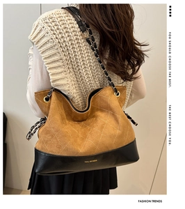 Detail of a large brown quilted suede tote bag with black leather bottom and chain strap