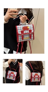 Detail of blue plaid canvas mini backpack featuring red apple print and leather straps