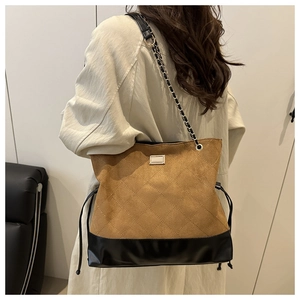 Detail of suede tote bag with diamond stitching, metal chain, and drawstring design