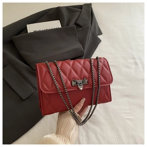 Detail of red quilted leather handbag with dark grey metal chain and vintage lock clasp