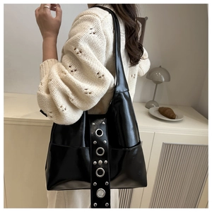 Detail of wide shoulder strap with silver metal grommets and rivets on black punk tote