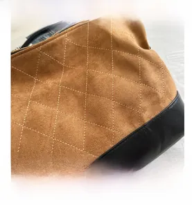 Macro detail of quilted brown suede and black leather bag with golden logo