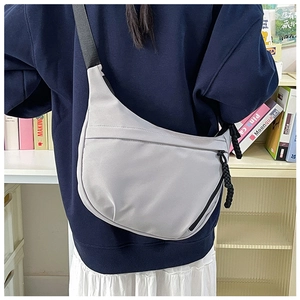 Detail of grey nylon crescent bag showing the adjustable black strap and knot zipper