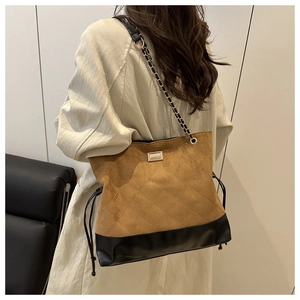 Detail of quilted brown suede tote bag with leather patchwork and gold chain strap